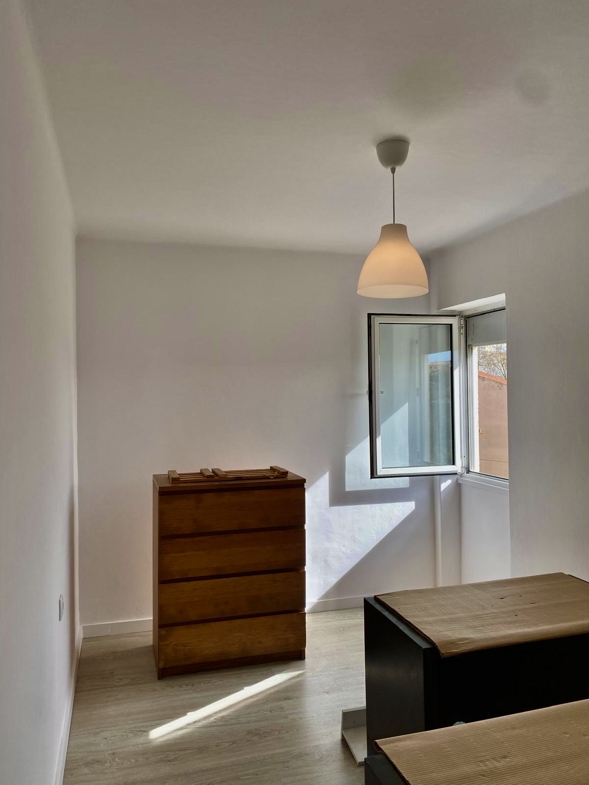 Quarto remodelado com paredes brancas e cómoda em madeira